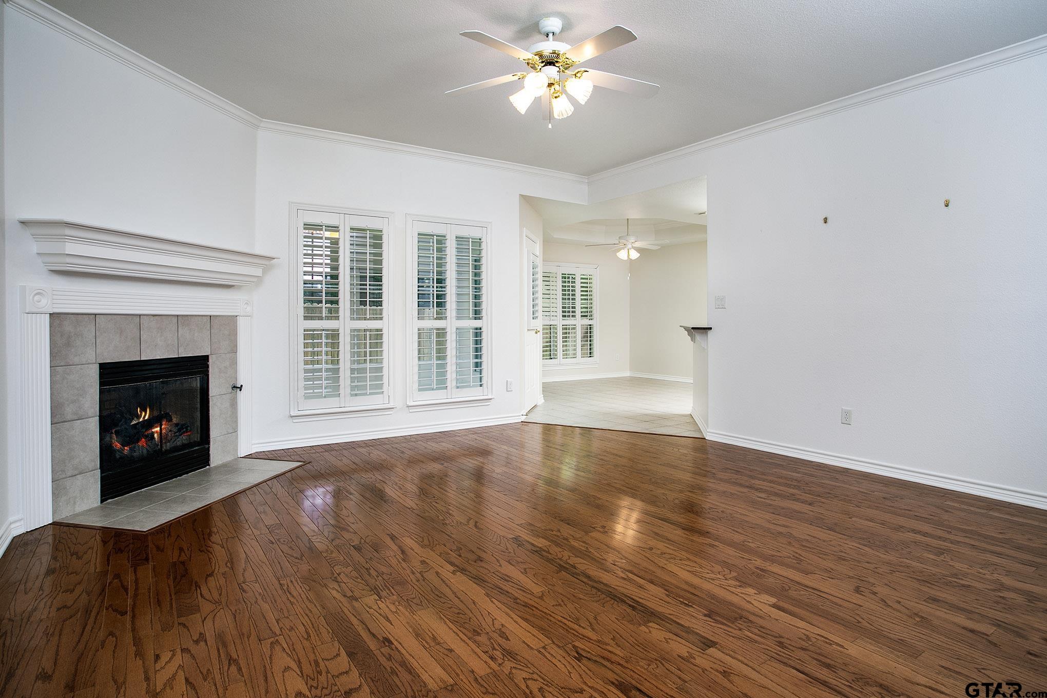 1521 Rice Road, Unit E105 Tyler, TX 75703 - Photo 7 of 32 a view of an empty room with wooden floor fireplace and a window