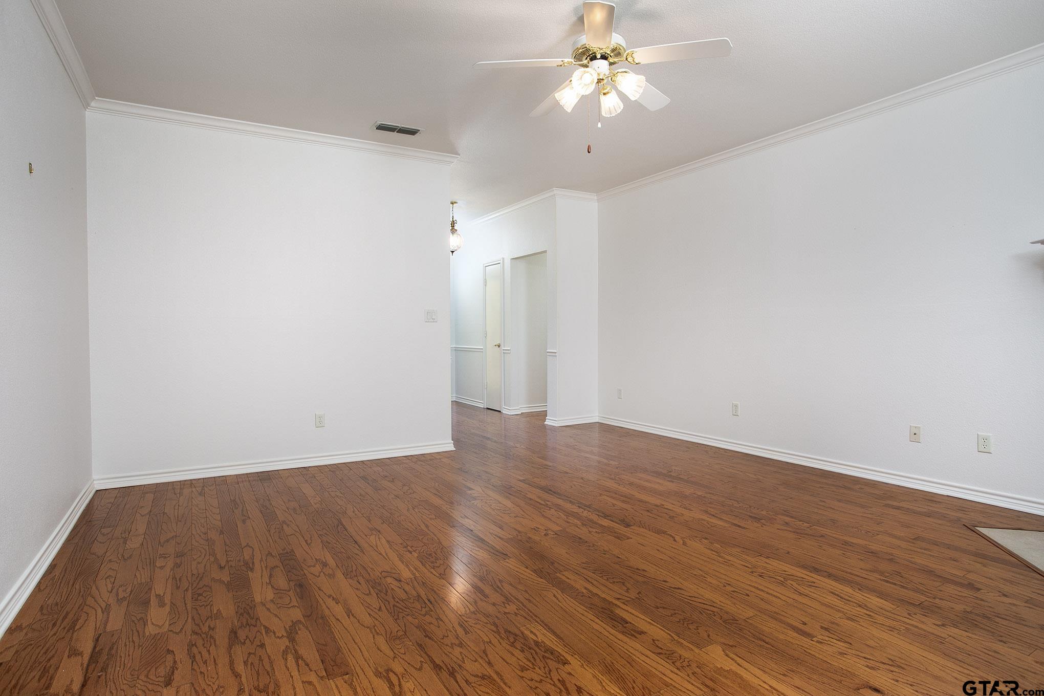 1521 Rice Road, Unit E105 Tyler, TX 75703 - Photo 8 of 32 an empty room with wooden floor and ceiling fan