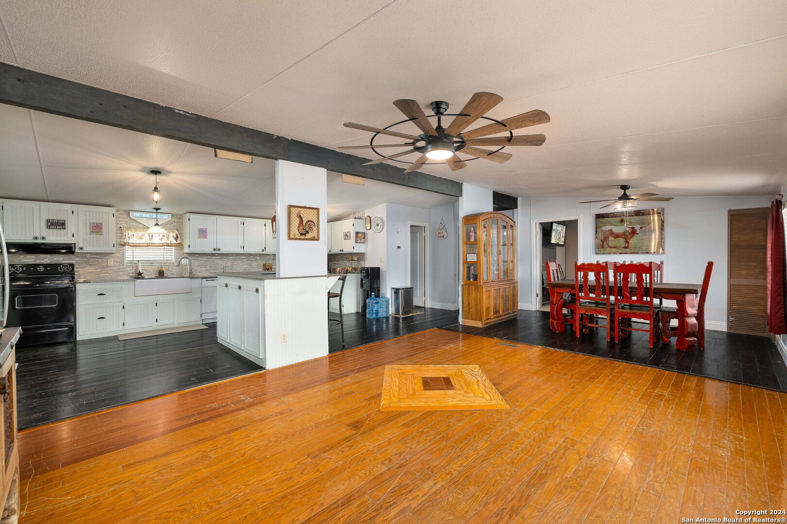 a large room with stainless steel appliances kitchen island granite countertop a sink cabinets and wooden floor