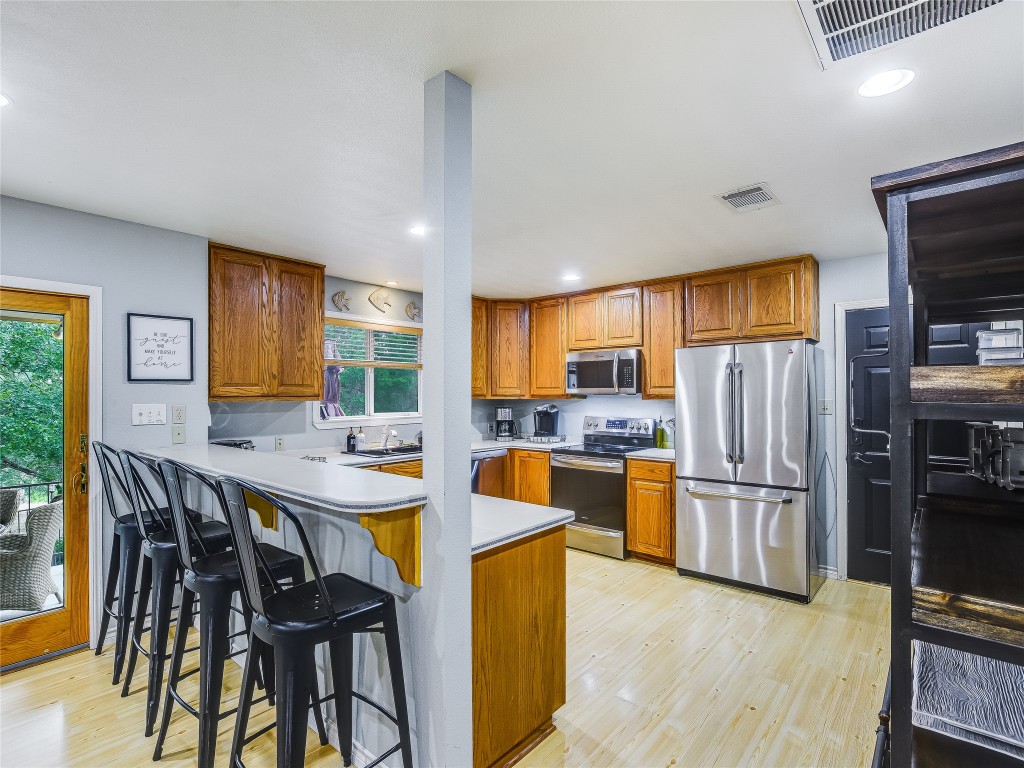 11000 Beach Road Leander, TX 78641 - Photo 9 of 38 a kitchen with stainless steel appliances granite countertop a refrigerator a stove a sink dishwasher and white cabinets with wooden floor