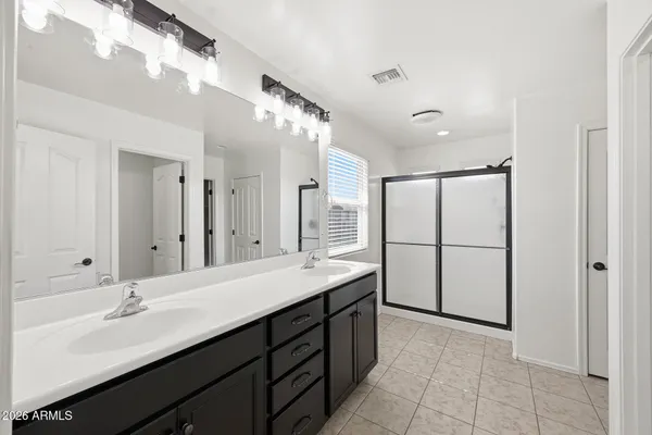 a bathroom with a double vanity sink a mirror and a shower