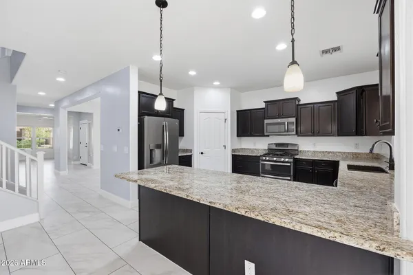 a large kitchen with granite countertop a large counter top stainless steel appliances and cabinets