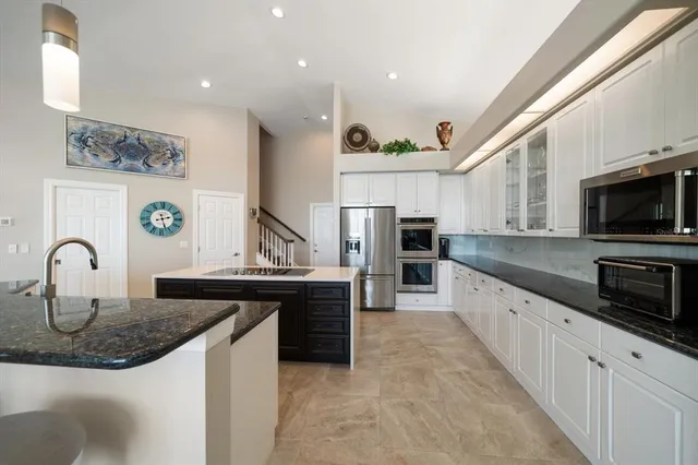 a view of a kitchen with kitchen island stainless steel appliances a sink a stove and center island