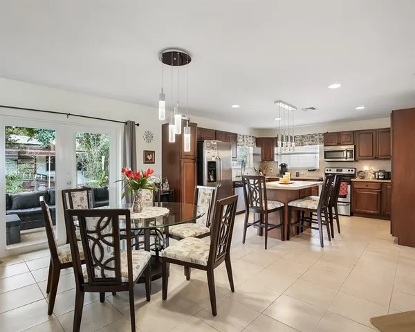a view of a dining room and livingroom with furniture a rug a painting and a chandelier