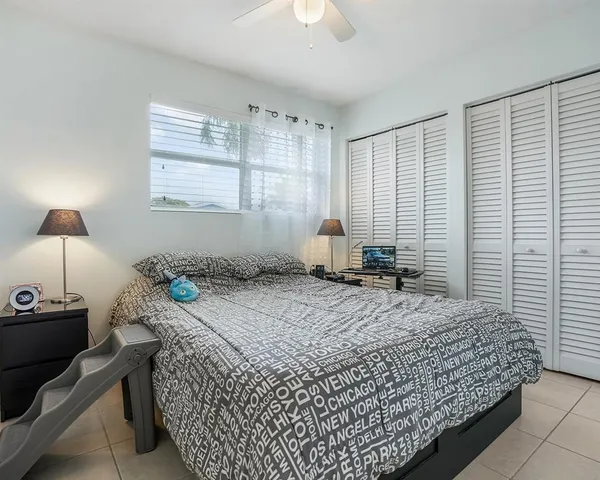 a bed sitting in a spacious bedroom next to a window and a lamp