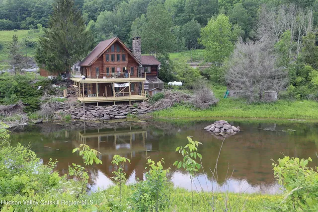 a view of a house with a yard and a pond
