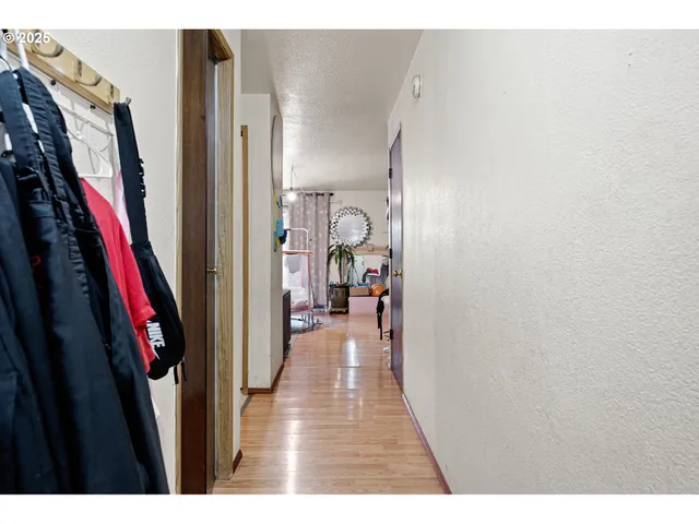 a view of a hallway with wooden floor and a bathroom with a sink