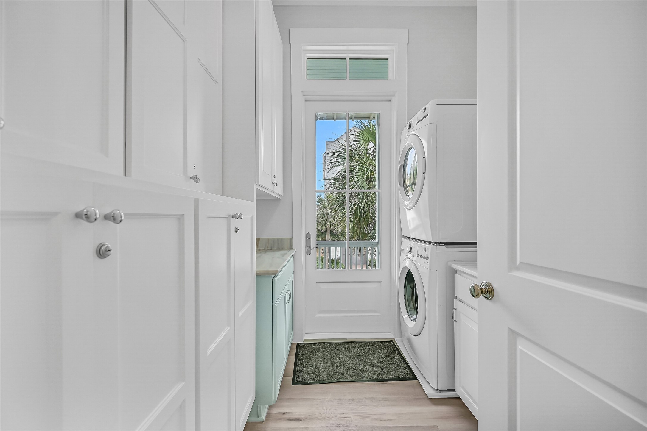 817 Positano Road Galveston, TX 77550 - Photo 40 of 50 Designed for convenience, the utility room features full-size washer and dryer connections, abundant storage cabinetry, and a utility sink for added functionality. A glass door welcomes natural light while providing easy access to the outdoors, making everyday tasks effortless and efficient.