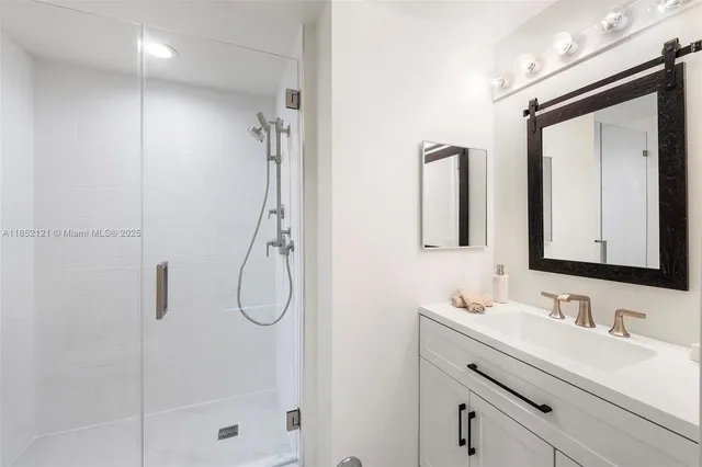 a bathroom with a granite countertop sink vanity mirror and shower