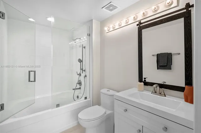 a bathroom with a sink a toilet a mirror and shower