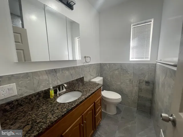 a bathroom with a granite countertop sink a toilet a mirror and window