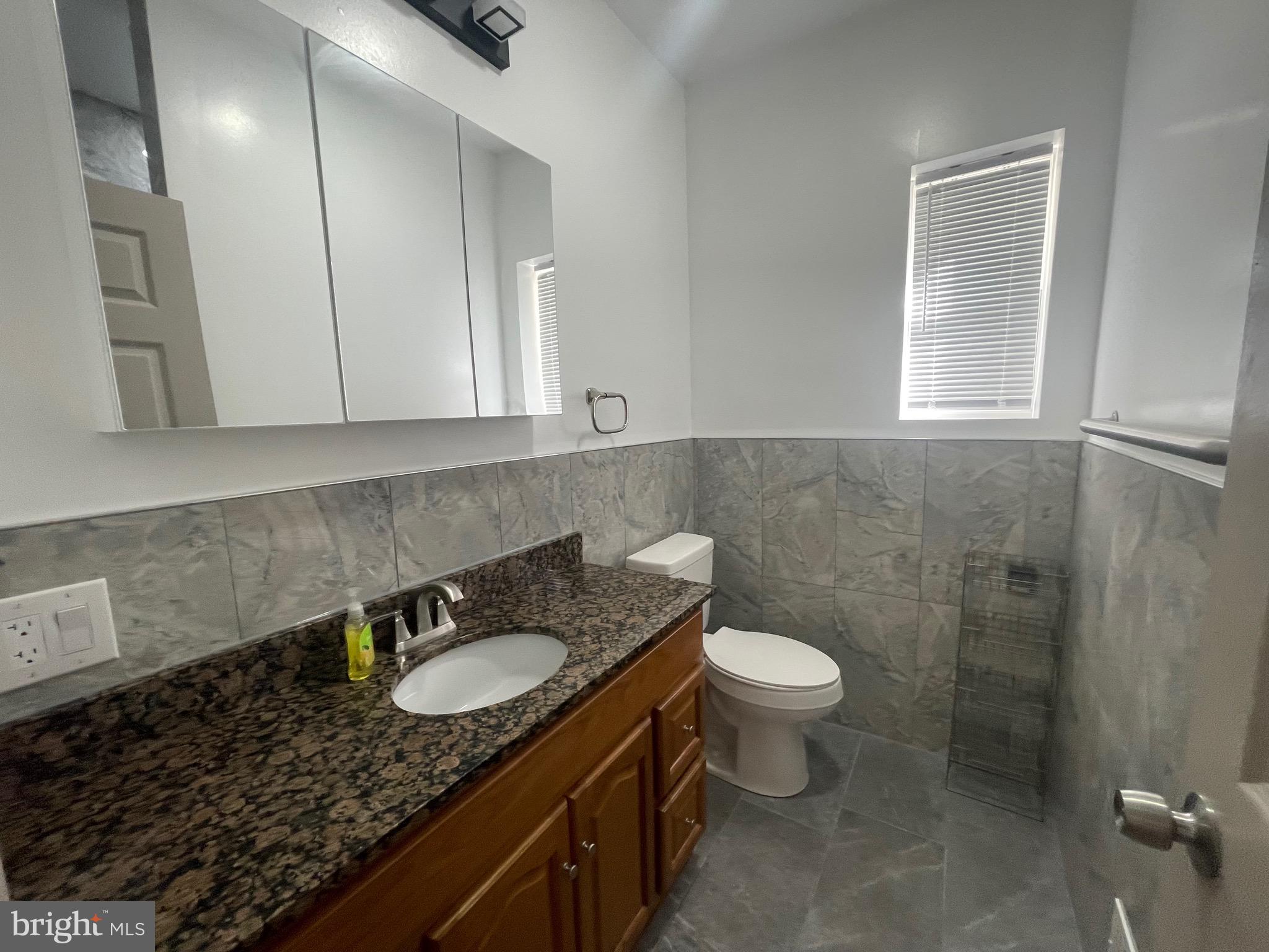 20 Pennsylvania Avenue, Unit 1 Reading, PA 19605 - Photo 8 of 17 a bathroom with a granite countertop sink a toilet a mirror and window