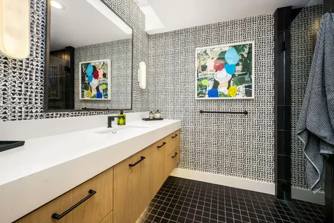 a bathroom with a sink a stove a painting on the wall and a shower