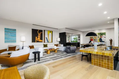a living room with furniture kitchen view and a large window