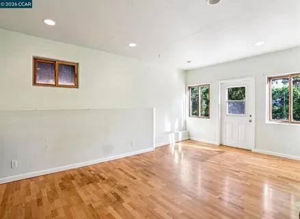 a view of empty room with wooden floor and fan