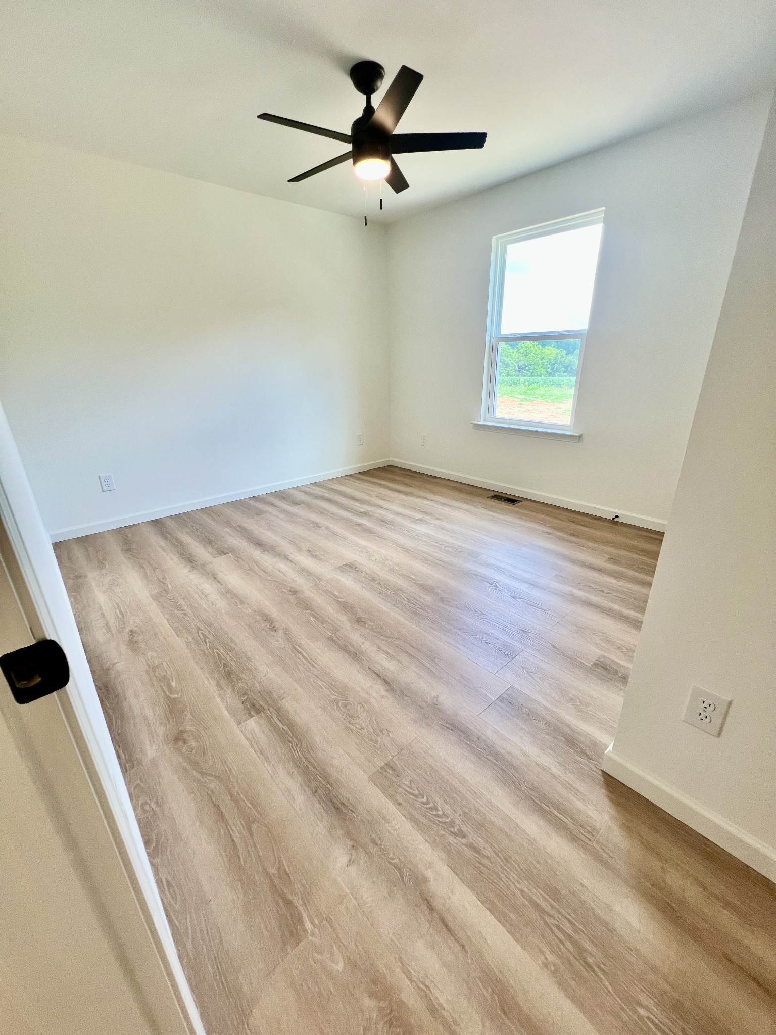 5712 Little Dry Creek Road Pulaski, TN 38478 - Photo 28 of 34 an empty room with wooden floor ceiling fan and windows