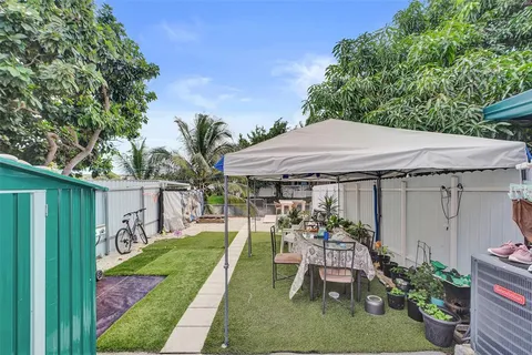 a view of a patio with table and chairs potted plants and large tree