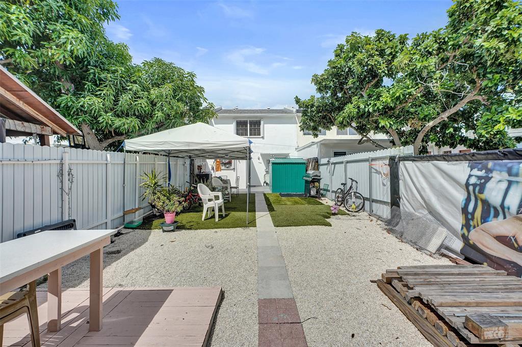 1732 West 72nd Street, Unit 1732 Hialeah, FL 33014 - Photo 45 of 58 a view of a patio with table and chairs under an umbrella with wooden fence