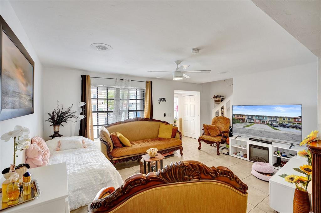 1732 West 72nd Street, Unit 1732 Hialeah, FL 33014 - Photo 7 of 58 a living room with furniture a flat screen tv and a floor to ceiling window