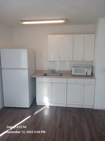 a kitchen with a refrigerator and white cabinets