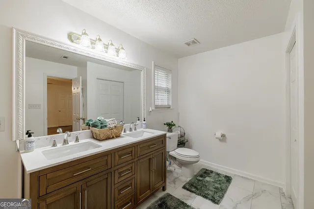 a bathroom with a double vanity sink toilet and shower