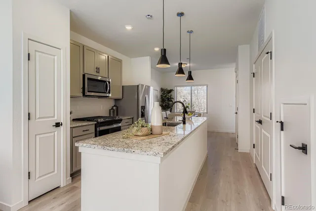 a kitchen with kitchen island granite countertop a sink a counter space appliances and cabinets