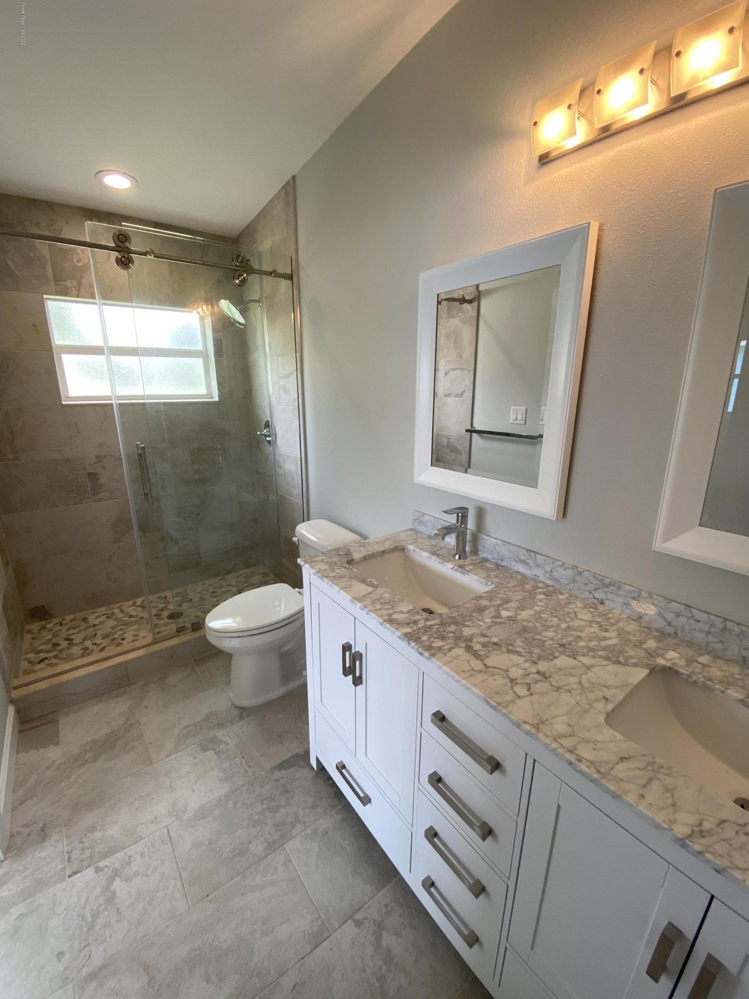 367 Capri Road Cocoa Beach, FL 32931 - Photo 19 of 27 a bathroom with a granite countertop sink a toilet a mirror and shower