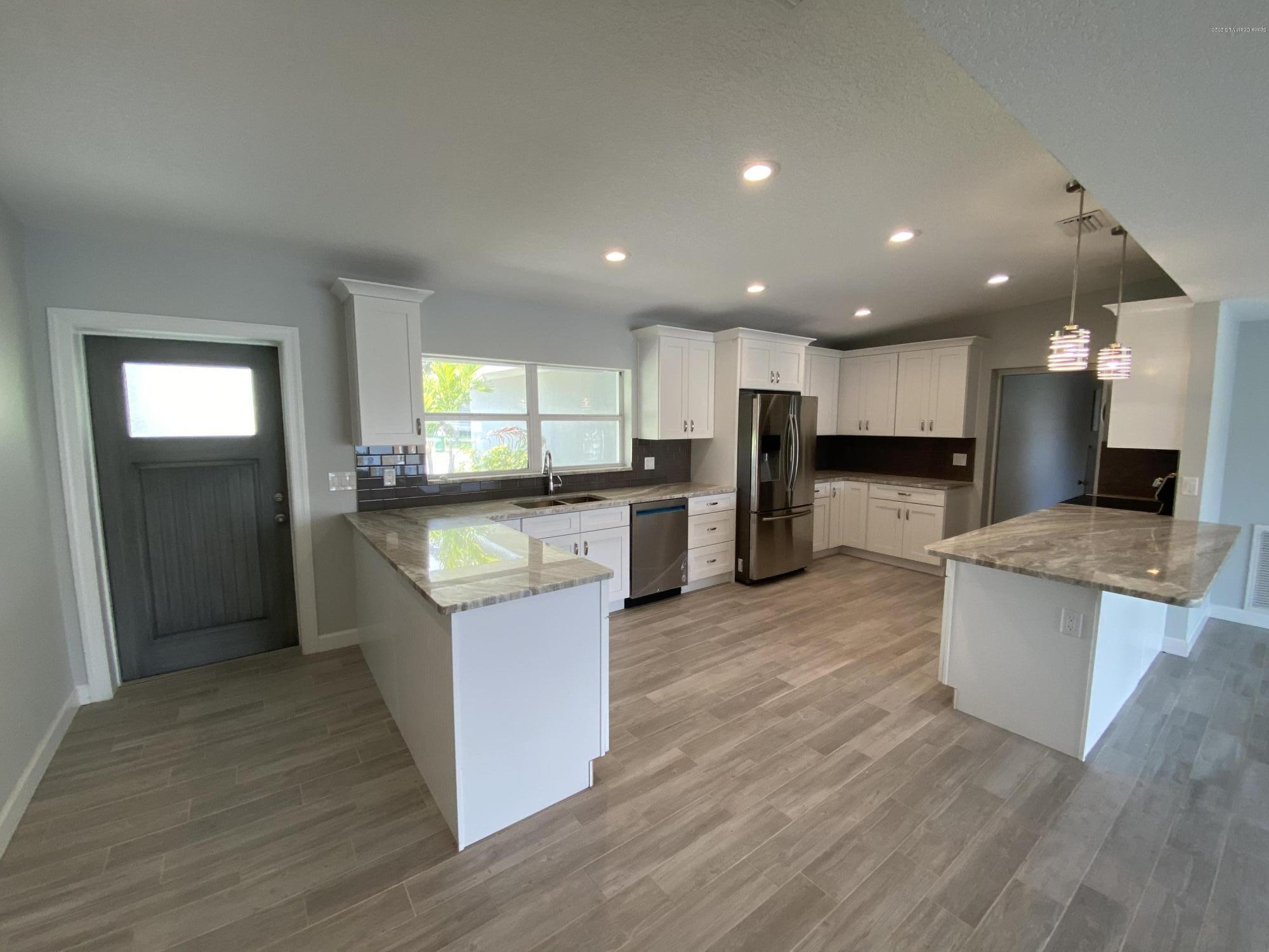 367 Capri Road Cocoa Beach, FL 32931 - Photo 4 of 27 a kitchen with stainless steel appliances kitchen island wooden cabinets and granite counter tops
