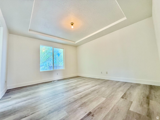 1705 80 East Tooele, UT 84074 - Photo 7 of 22 Spacious room featuring a tray ceiling with recessed lighting, wood-finish flooring, and white baseboards