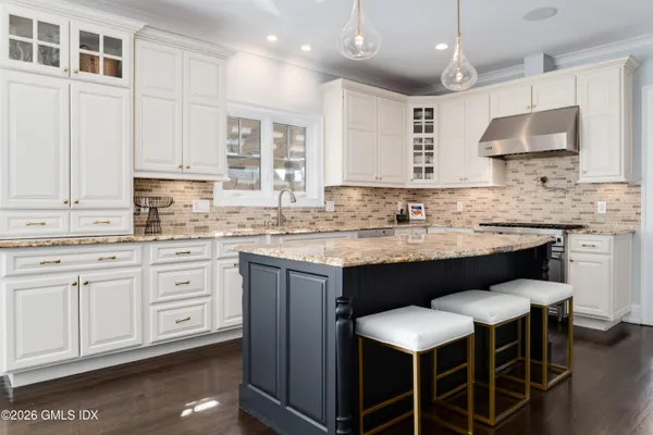 a kitchen with granite countertop a sink stove and white cabinets