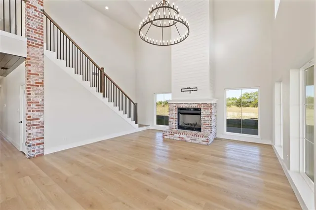 a view of an empty room with wooden floor fireplace and a window