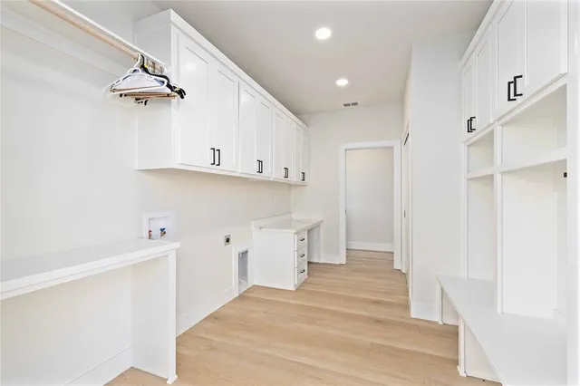 a view of a kitchen with white cabinets and wooden floors