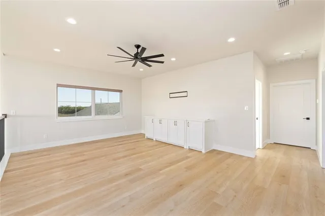 a view of empty room with wooden floor and fan