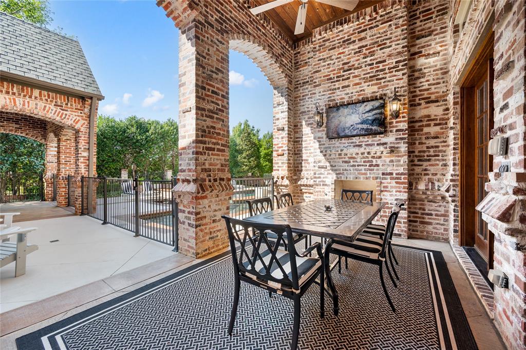 6900 Rockingham Court Colleyville, TX 76034 - Photo 32 of 40 Covered Patio #1 of 4 off of Formal Living Room features brick archways, a television, and a wood-paneled ceiling with a ceiling fan.