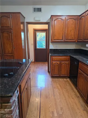 a kitchen with granite countertop wooden cabinets a sink and dishwasher
