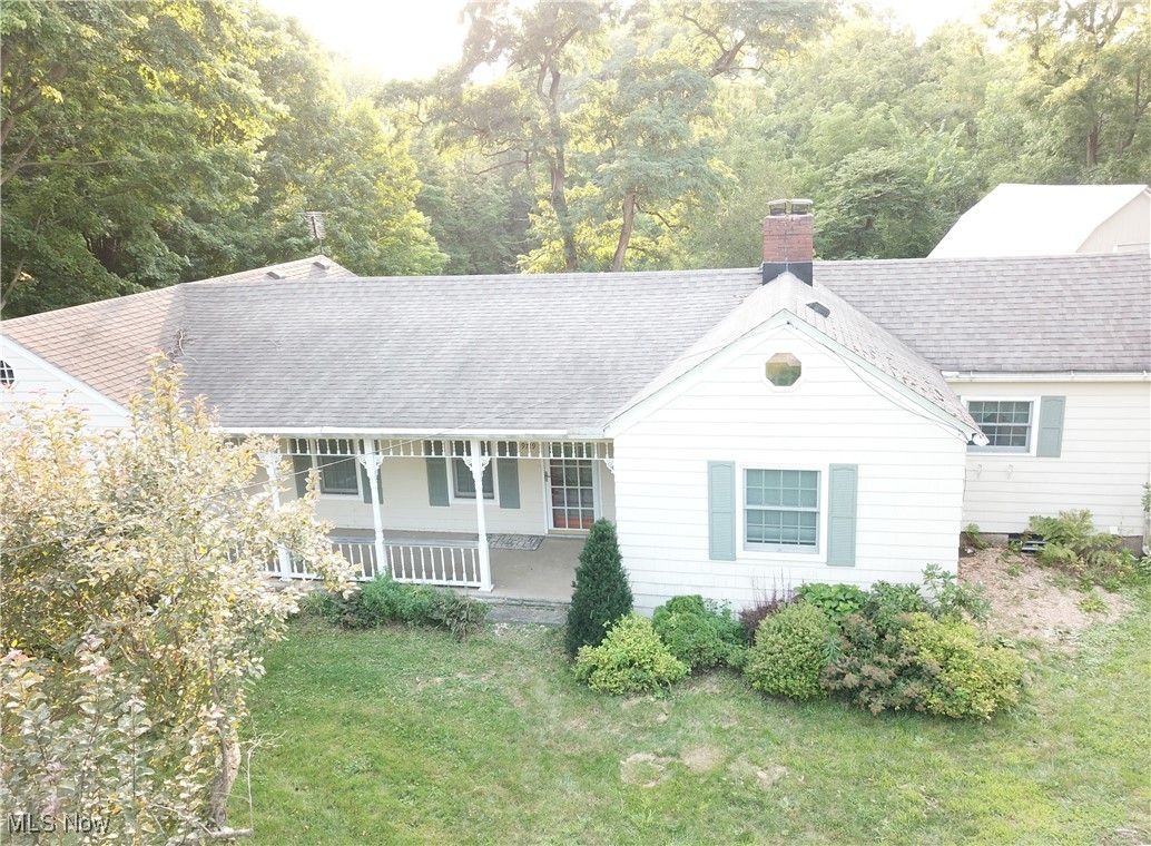 9719 Angling Road Wakeman, OH 44889 - Photo 3 of 39 View of front of house featuring a chimney, covered porch, a front yard, a forest view, and a shingled roof
