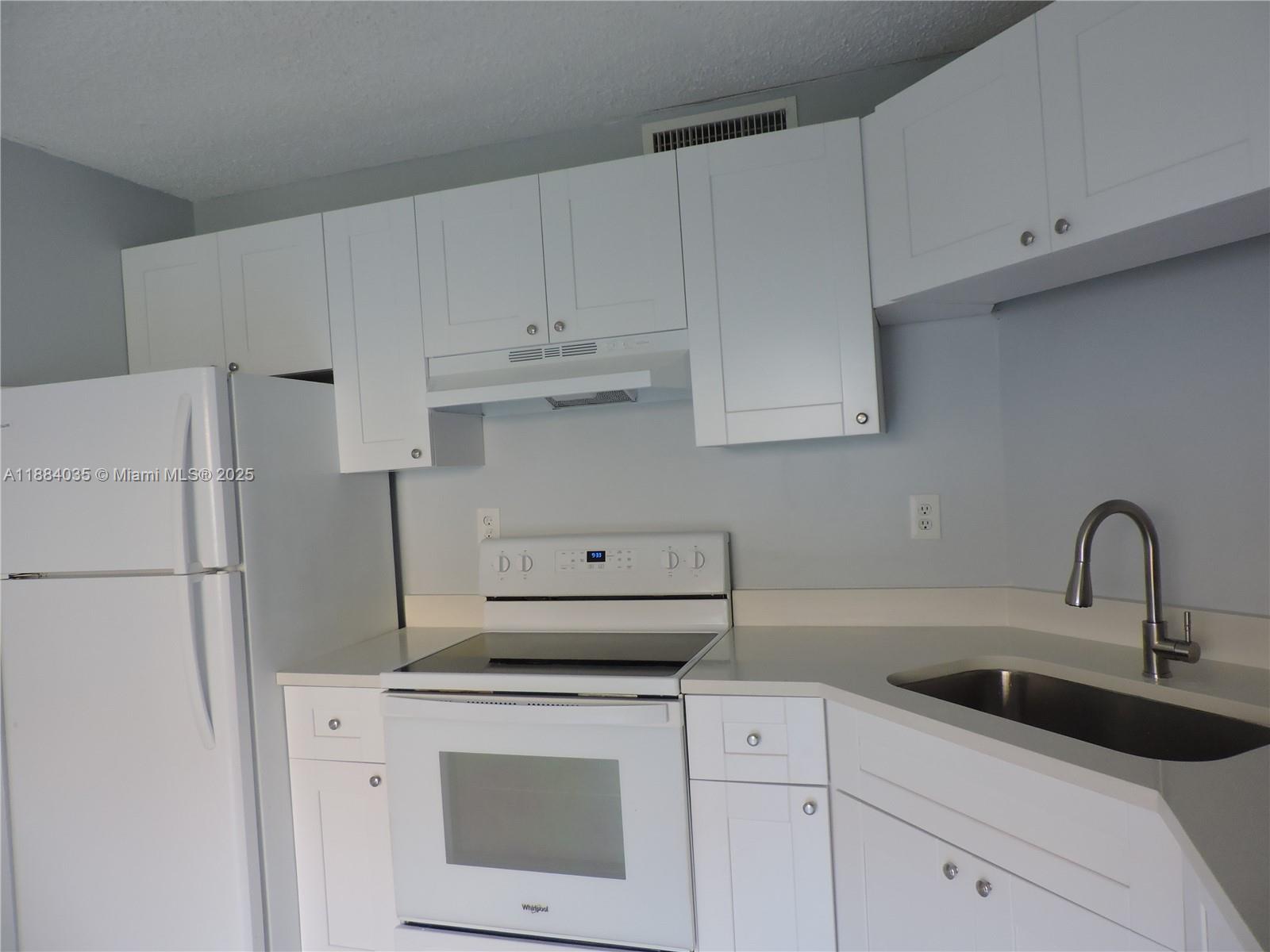 13045 Southwest 68th Street, Unit 104 Miami, FL 33183 - Photo 11 of 16 a kitchen with white cabinets sink and white appliances