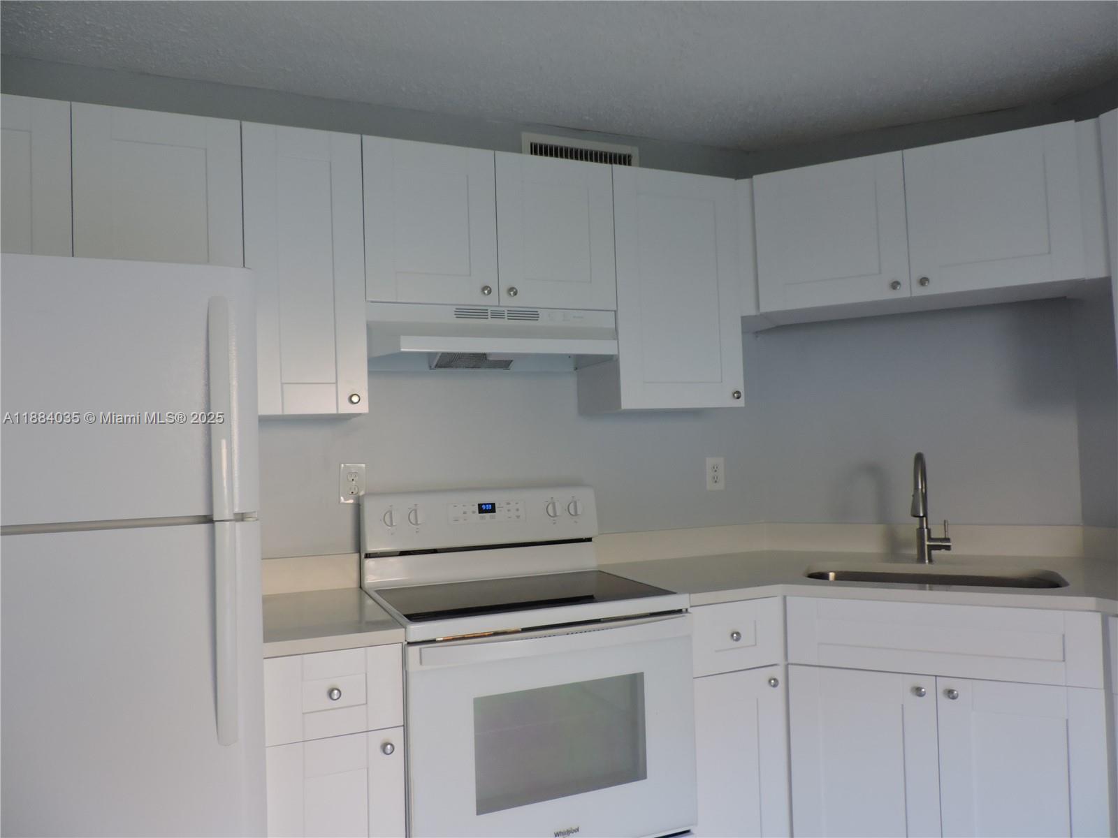 13045 Southwest 68th Street, Unit 104 Miami, FL 33183 - Photo 10 of 16 a kitchen with white cabinets and appliances