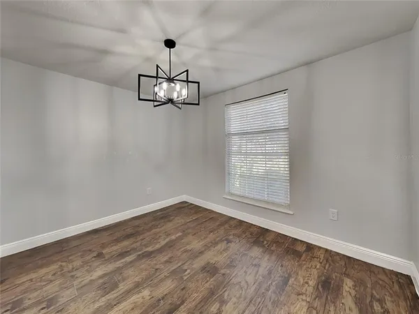 a view of empty room with wooden floor chandelier