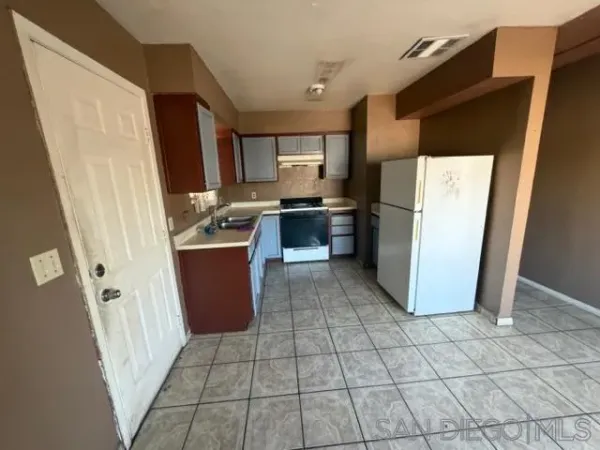 a kitchen with a refrigerator a stove top oven and cabinets