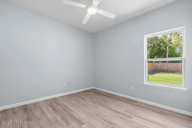 an empty room with wooden floor chandelier fan and closet