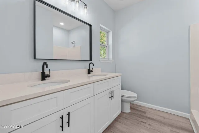 a bathroom with a granite countertop toilet a sink and a mirror
