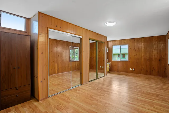 a view of an empty room with wooden floor and a bathroom