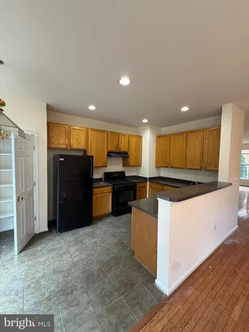 a large kitchen with stainless steel appliances kitchen island granite countertop a refrigerator and a stove top oven