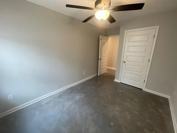 an empty room with closet and a ceiling fan