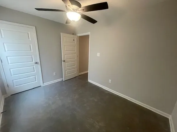 an empty room with a chandelier fan and windows