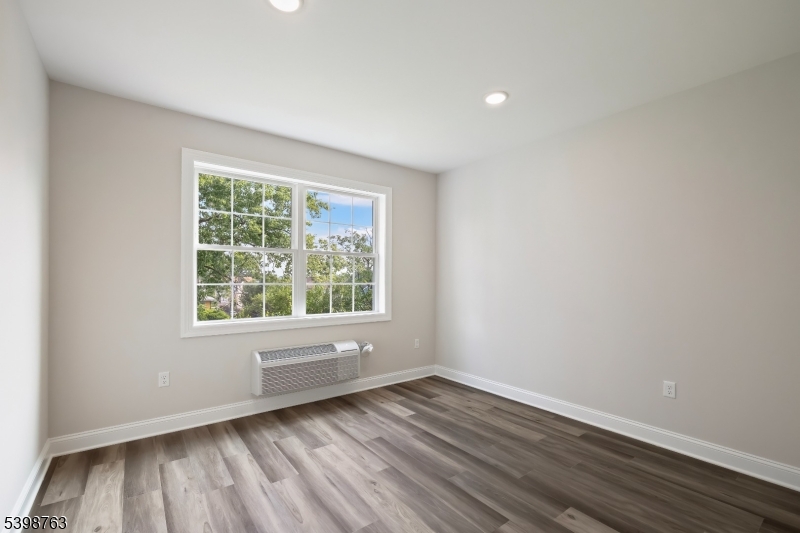 60 Woodside Place, Unit 4C Newark, NJ 07104 - Photo 8 of 14 an empty room with wooden floor and windows
