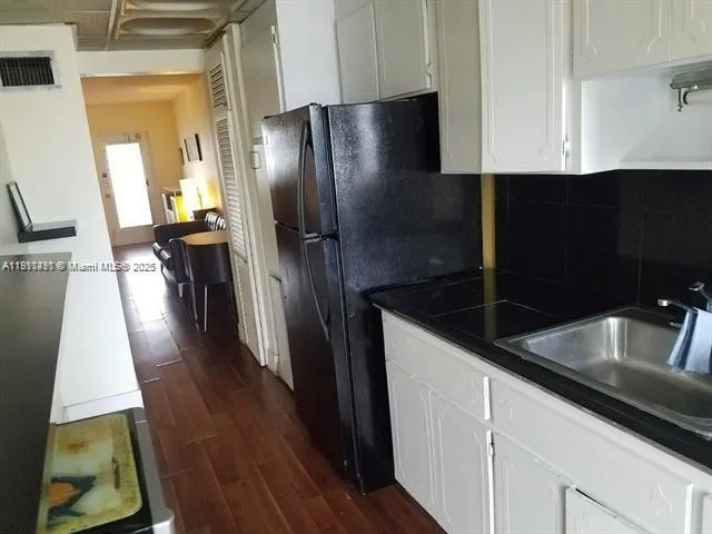 a kitchen with stainless steel appliances granite countertop a refrigerator a sink a stove and white cabinets