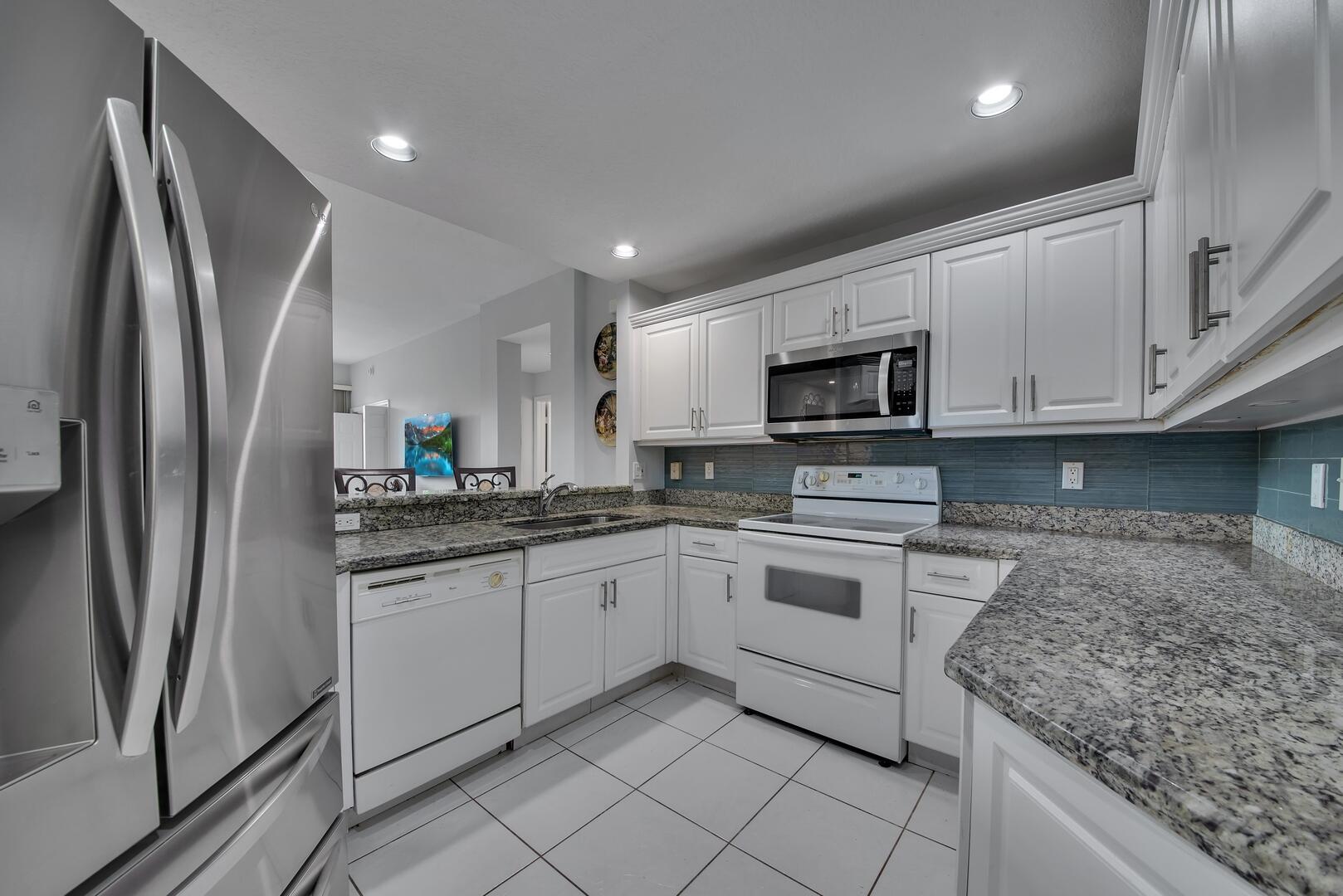 12438 Crystal Pointe Drive, Unit 102 Boynton Beach, FL 33437 - Photo 10 of 39 a kitchen with stainless steel appliances granite countertop a refrigerator sink and microwave