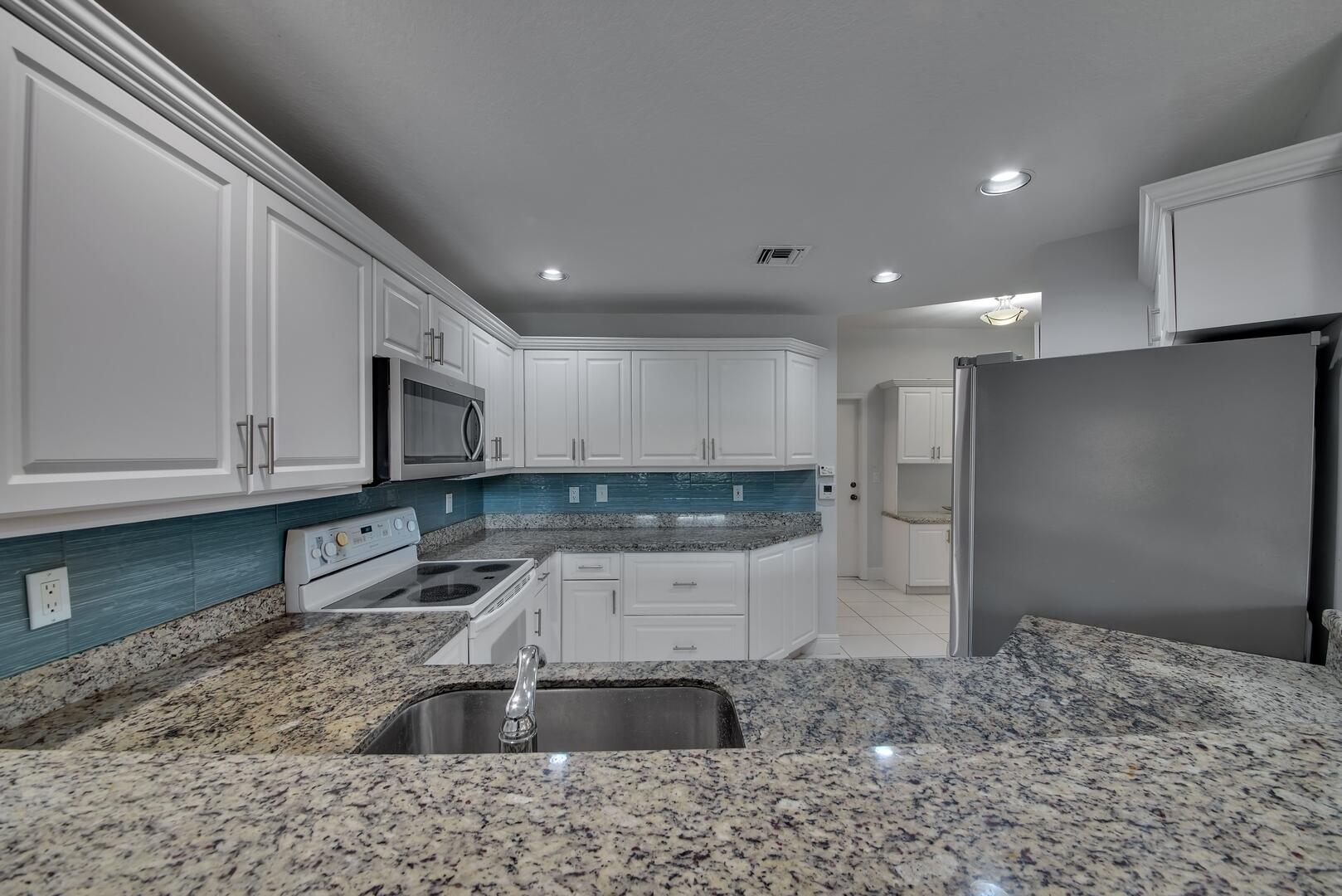 12438 Crystal Pointe Drive, Unit 102 Boynton Beach, FL 33437 - Photo 11 of 39 a kitchen with stainless steel appliances granite countertop a sink a stove and a refrigerator